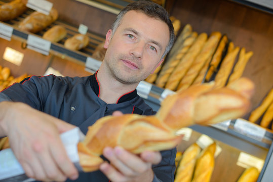 baker selling fresh bread baguettes in bakery