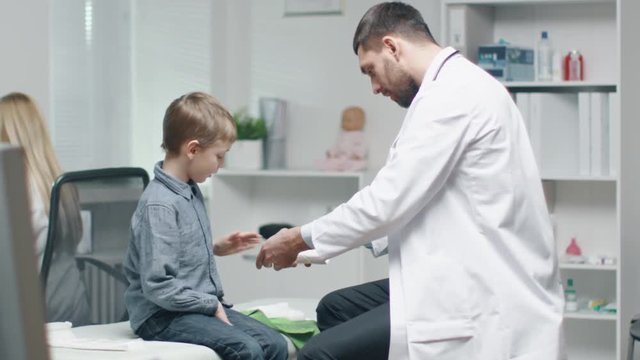 Male Doctor Removes Plaster from a Boy's Healed Hand. Boy is Very Happy. They Do High Five. In Slow Motion. Shot on RED Cinema Camera in 4K (UHD).