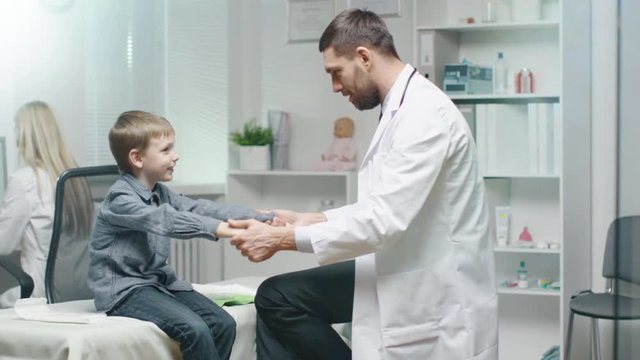 Male Doctor Checks Young Boys Muscle Tone in Hands. After Check-up They High Five.  Shot on RED Cinema Camera in 4K (UHD).