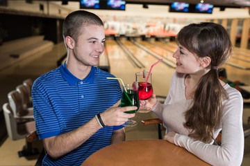 young couple on a date behind table in bowling club