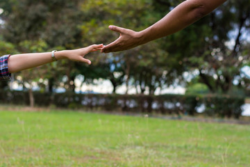 Woman sitting on the grass reaching to shake the hand of man. helping hand and love concept.