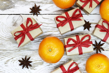 gift packages wrapped in gray paper with organic red ribbon, nectarines and anise on the wooden background