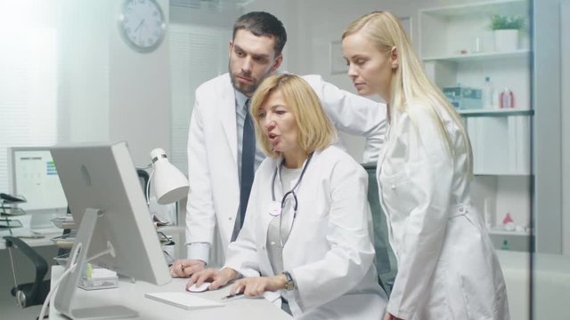 Group of Three Medical Specialists Solving Problems at the Desktop Computer. They Gesticulate and Point at the Screen. Shot on RED Cinema Camera in 4K (UHD).