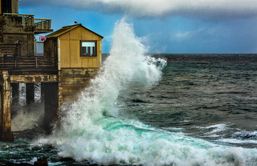 Wave hits a pier at Cannery Row in Monterey