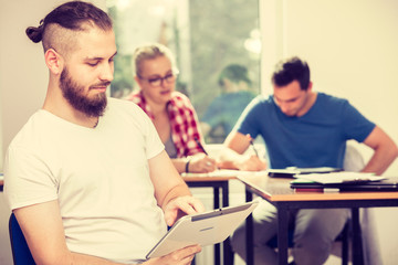 Fototapeta premium Male student with tablet in front of her classmates