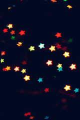 Fototapeta premium Christmas, New Year background with beautiful stars bokeh of colorful garland lights