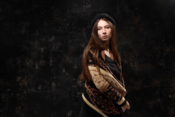 Pretty girl in fashionable clothes on a black background textured wall