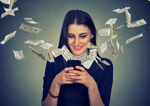 woman using smartphone with dollar bills flying away from screen.