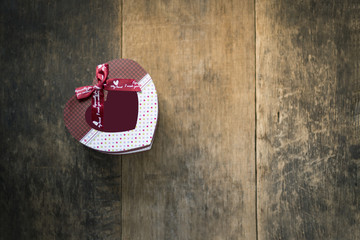 Heart gift box tied with red bow on wooden background
