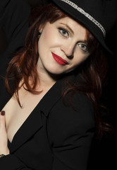 Beautiful woman in black hat and jacket on a dark background.