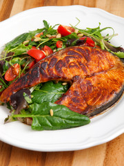 Baked marinated salmon with fresh salad of arugula and cherry to