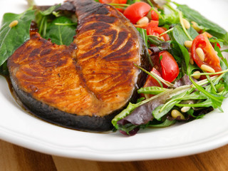 Baked marinated salmon with fresh salad of arugula and cherry to