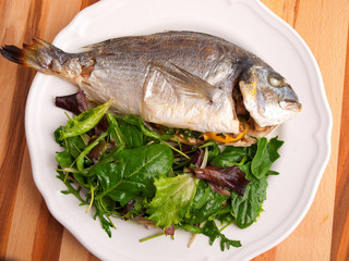 Baked sea bream with green salad shot from above