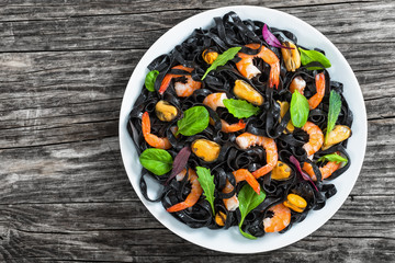 black noodles salad with prawns, mussels, spinach, lettuce, arug