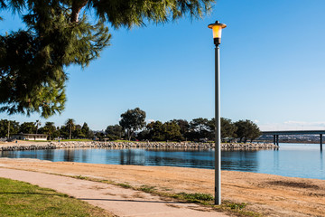 Sidewalk winding through Vacation Isle Park with Mission Bay of San Diego, California in the background.