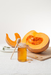 cut pumpkin and honey on a light wooden background