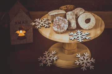 Traditional Spanish Christmas cookies polvorones, nevaditos and mantecados on a wood cake stand, lit candle, selective focus, toned