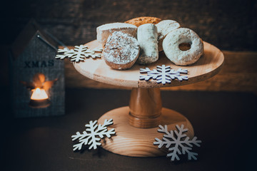Traditional Spanish Christmas cookies polvorones, nevaditos and mantecados on a wood cake stand, lit candle, selective focus
