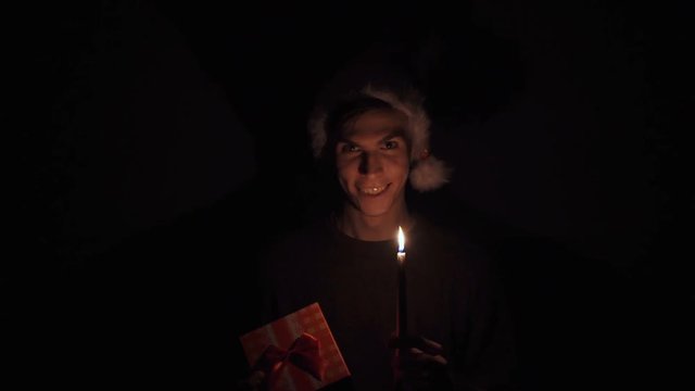 Young man in Santa hat looks like the Grinch rubbing their hands gloating