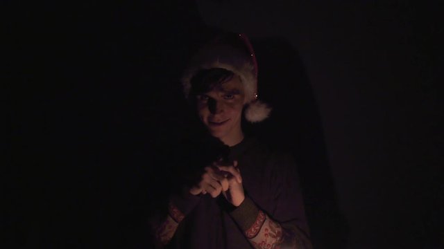 Young man in Santa hat looks like the Grinch rubbing their hands gloating