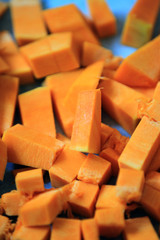 Fresh sliced hokkaido pumpkin cubes prepared for cooking on baking paper.