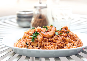 Tasty risotto with Shrimp, fresh herbs vegetables on a white pla