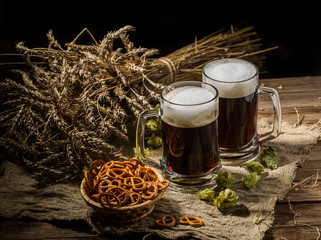 Couple beer mug with hop and pretzels on linen cloth