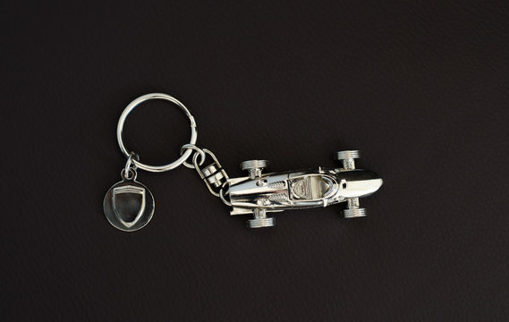 Silver-chrome keychain with an  old super fast model on leather background