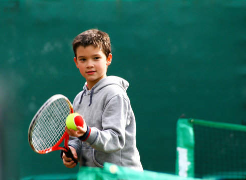 Little tennis player on a blurred green background