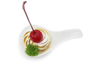 Whipped cream in a white spoon. Topping is cherry. Decorate with parsley. 