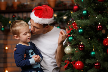 Father kissing son near pine