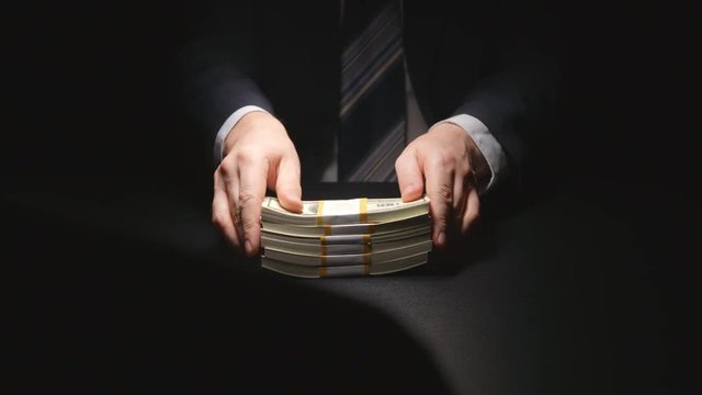 Bribe: Businessman hesitate puts out a money bundle on a table - two person