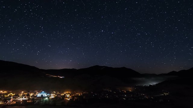 Night traffic in village and street lights under starry sky time lapse