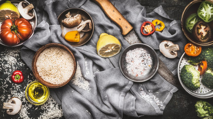 Healthy vegetarian food ingredients with lemon, rice and vegetables on dark rustic background, top view