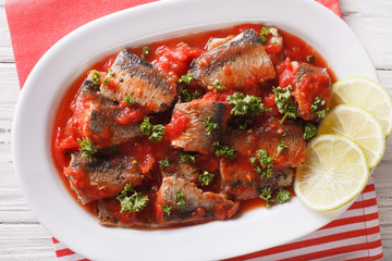 Tasty sardines in tomato sauce with lime and parsley close-up. horizontal top view