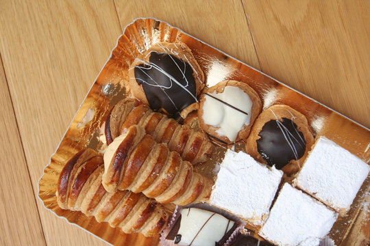 Pasticceria italiana, Pasticcini alla crema o cioccolato su vassoio su tavolo di legno