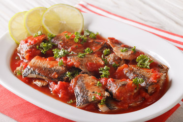 Braised sardines in tomato sauce with lime and parsley close-up. horizontal