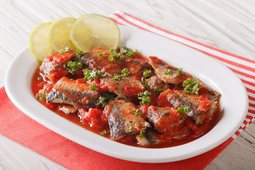 Tasty sardines in tomato sauce with lime and parsley close-up. Horizontal