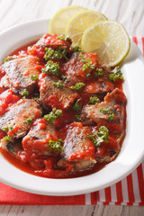 Delicious sardines in tomato sauce with lime and parsley close-up. vertical