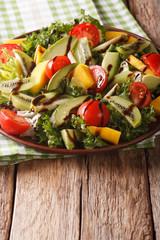 salad of mango, avocado, kiwi, lettuce, tomato dressed with balsamic sauce closeup. vertical