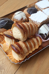 Pasticceria italiana, Pasticcini alla crema o cioccolato su vassoio su tavolo di legno