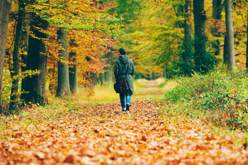 Fototapeta premium Female tourist walking in autumn forest.