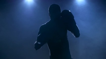 Sportsman boxing in smoky studio. Silhouette on a dark background - Powered by Adobe