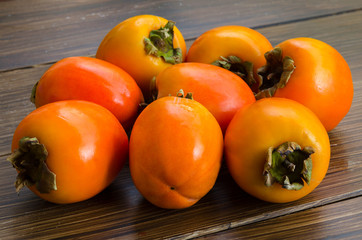 Group of organic persimmon fruit on rustic wood background. Concept for healthy food, vegan or raw diet.