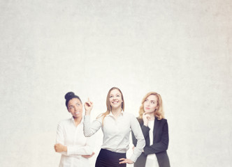 Three women brainstorm near concrete wall