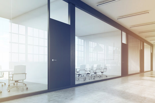 Long office corridor with a row of conference rooms, toned