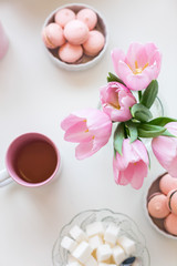 Spring background. Sweets and tea on a table with pink tulips. Still life with fresh bouquet of tulips. Beautifully decorated tray with a bouquet of tulips and a Cup of tea.