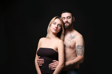 Portrait of romantic tattooed couple on black background