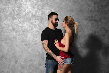 Portrait of young tattooed couple on gray wall background