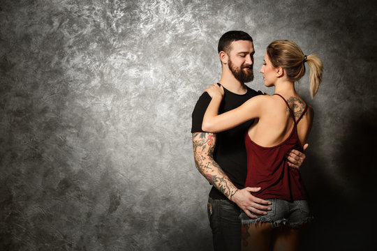 Portrait of young tattooed couple on gray wall background